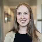 Alicia Reed, with long hair, a black top and tan sweater.