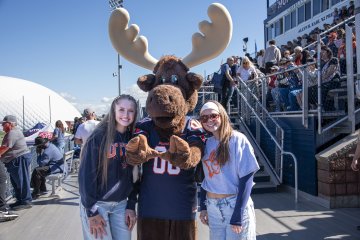 Students stand next to Trax near the bleachers of Gaetano Stadium.