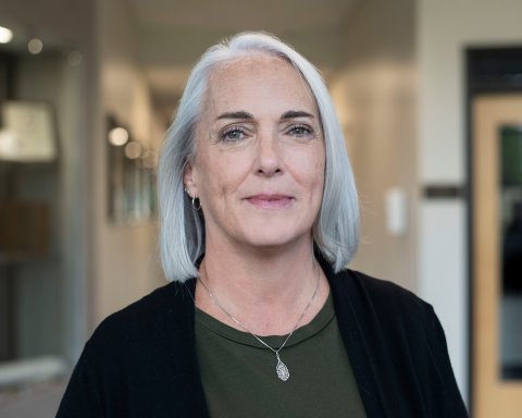 Beth Ricci with shoulder-length light hair, green top and black sweater.