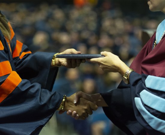 Graduate and President shake hands as diploma is received.