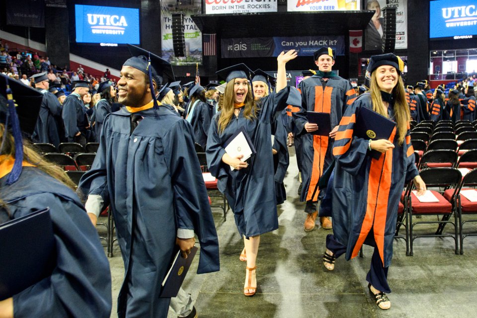 A graduate waves as members of the graduate class of 2022 exits the ceremony with their degrees.